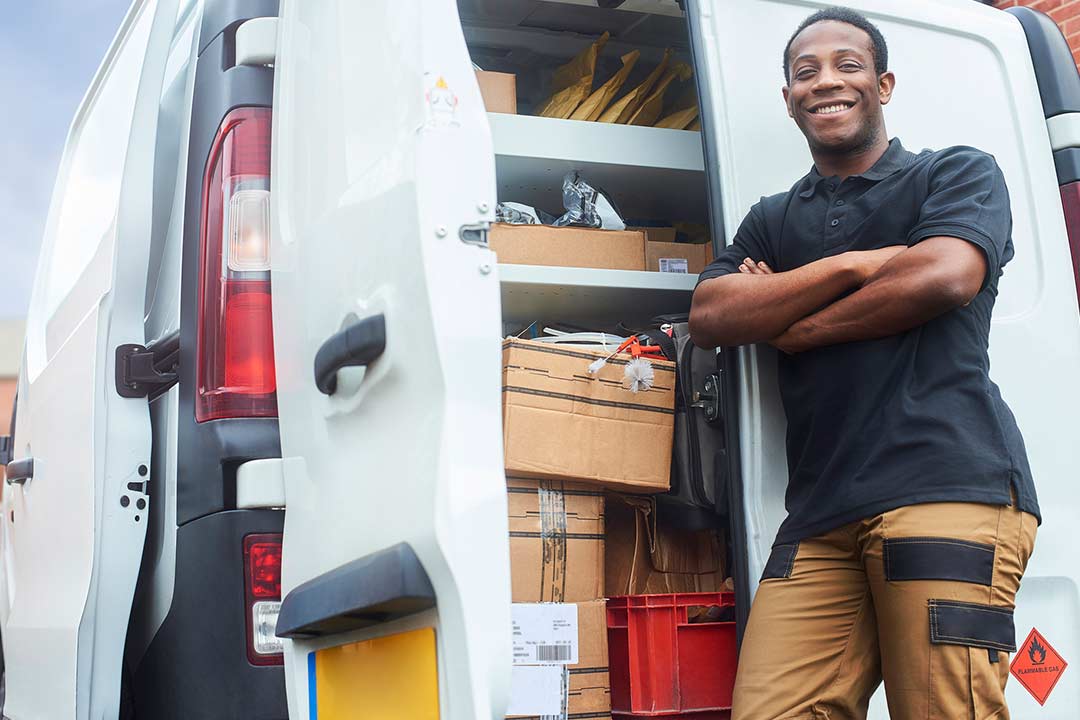 A male handyman standing behind his utility van