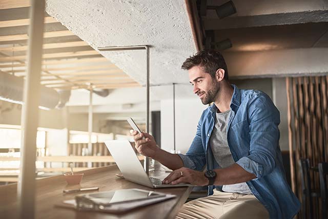 Young business person checking their mobile phone while working